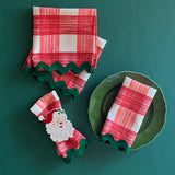 Gin Lane Geranium Red w/ green Ric Rac cloth Dinner Napkins shown on a green plate and one gathered into a Santa napkin ring.