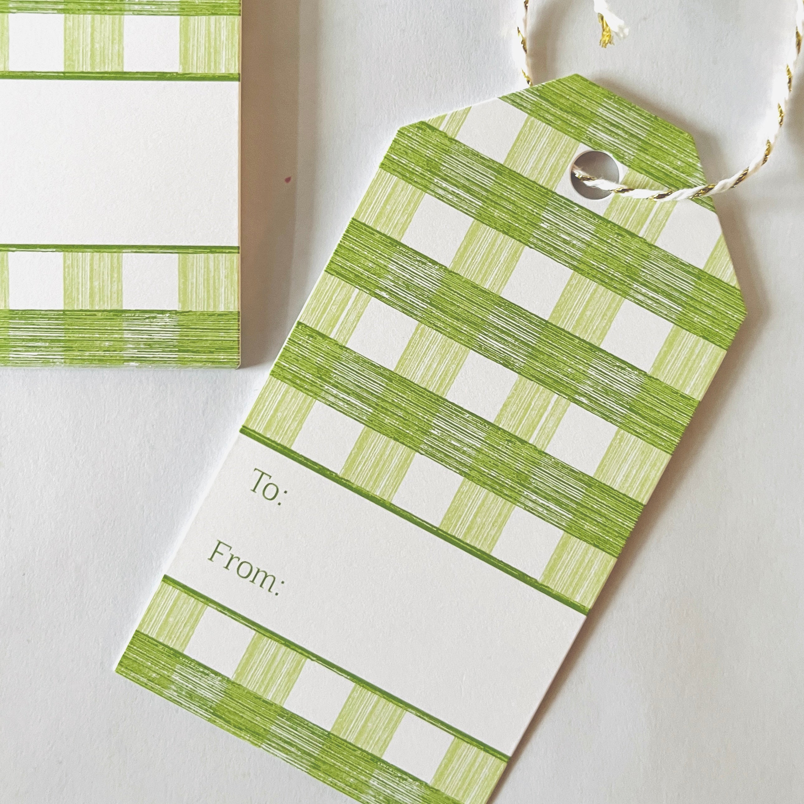 A green gingham patterned gift tag with a white space for personalization on the back, displayed on a white background.