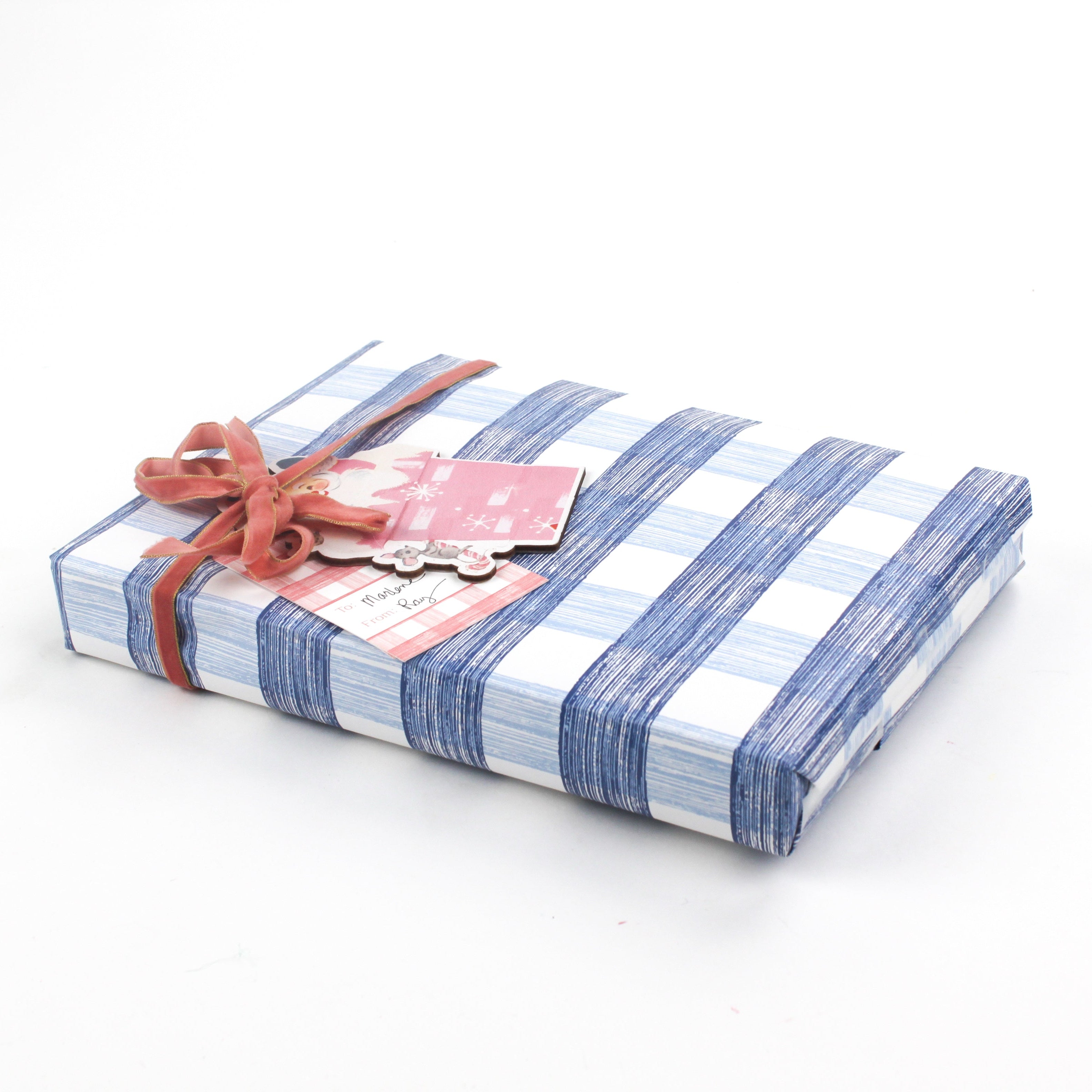 Gift wrapped in blue gingham Christmas paper with a pink ribbon and festive gift tag.