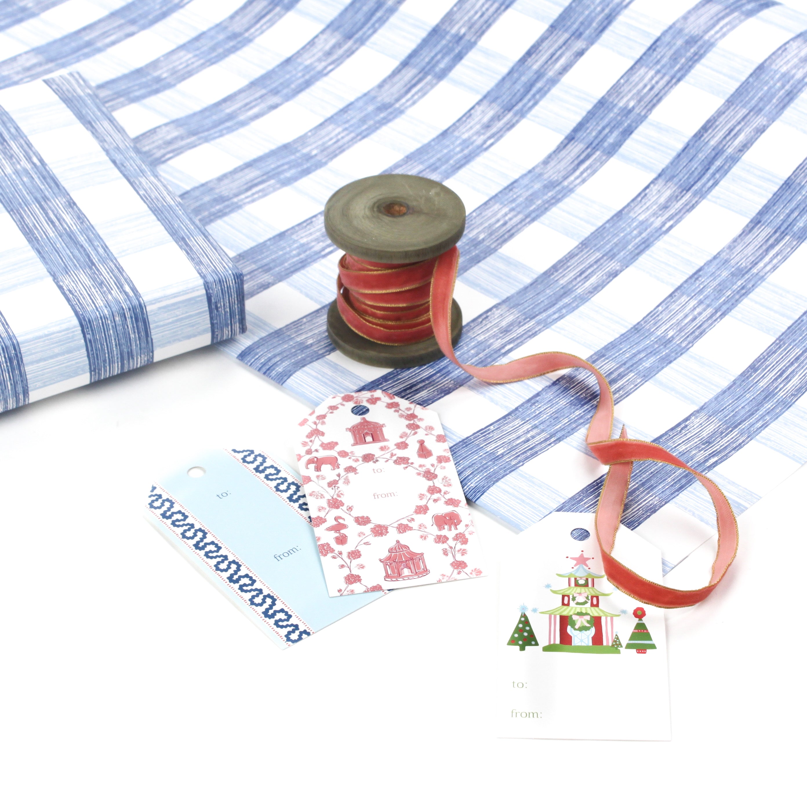Blue gingham Christmas wrapping paper with ribbon and gift tags on display.