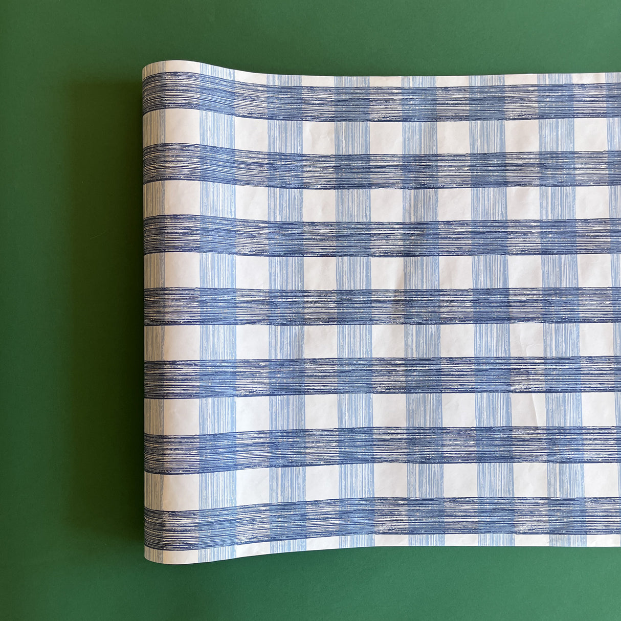 A blue gingham paper table runner on a green background. 