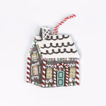 Brown gingerbread house Christmas ornament with a white icing roof, red and white candy cane details, colorful candy accents, and a red and white hanging string.
