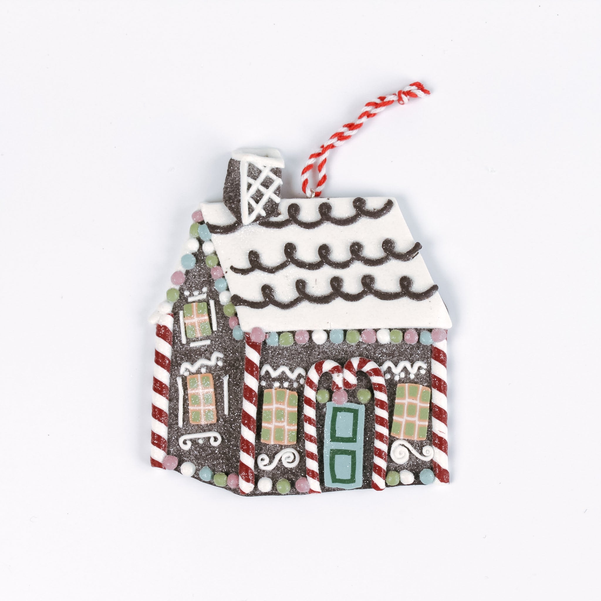 Brown gingerbread house Christmas ornament with a white icing roof, red and white candy cane details, colorful candy accents, and a red and white hanging string.