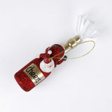 top view of a santa riding a red champagne bottle christmas ornament against a white background