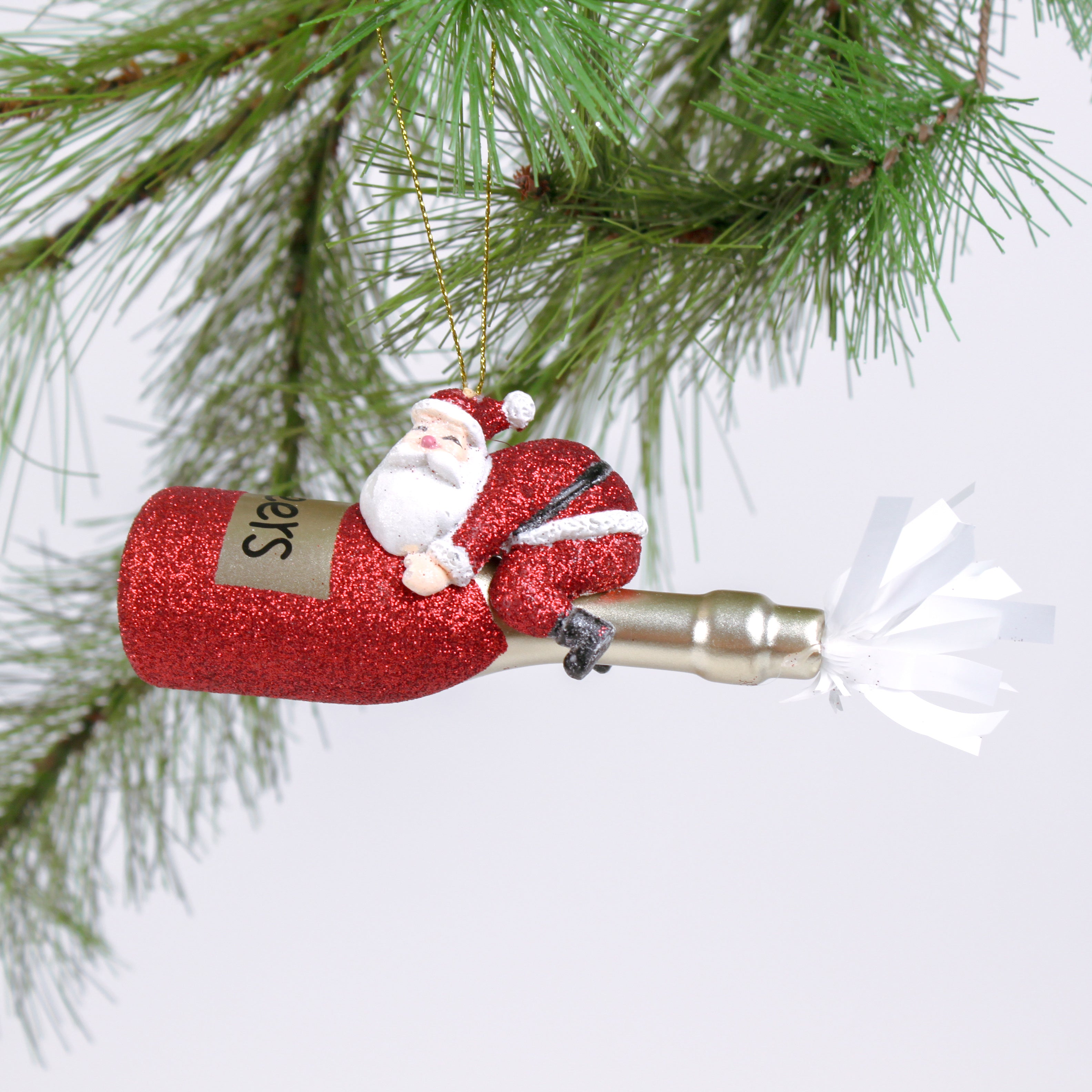 a santa riding a red champagne bottle ornament against a white background