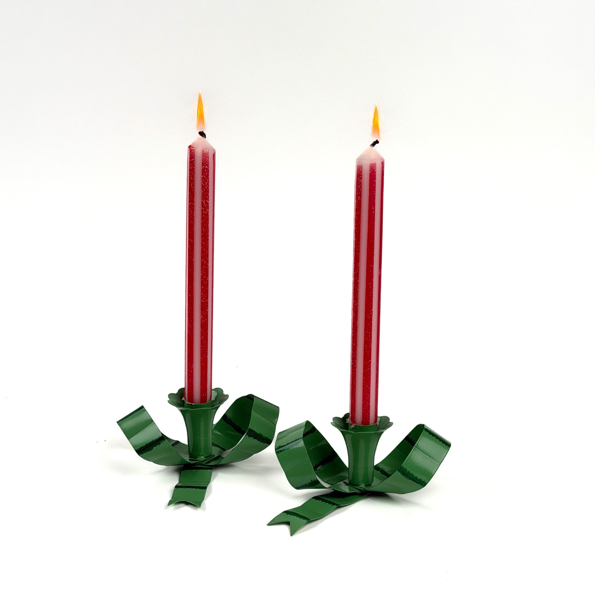 set of green bow-shaped candleholders with lit red taper candles