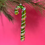 green glass candy cane ornaments on a pink background