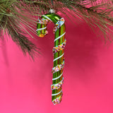 green glass candy cane ornaments on a pink background