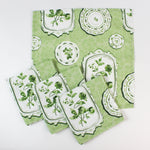 Set of green patterned fabric napkins with vintage plate and botanical designs.