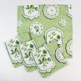 Set of green patterned fabric napkins with vintage plate and botanical designs.