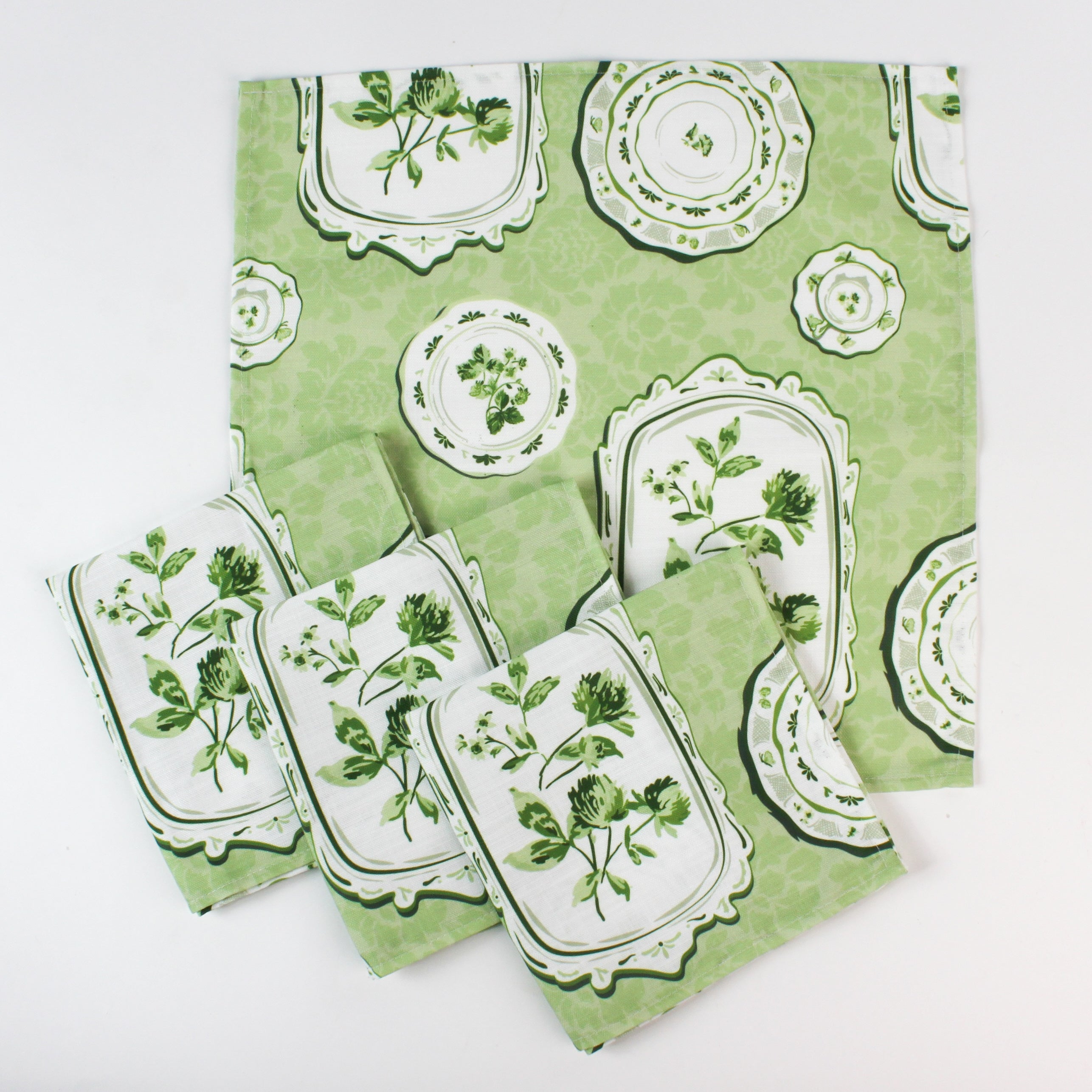 Set of green patterned fabric napkins with vintage plate and botanical designs.