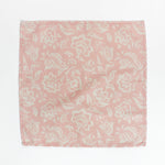 Pink and cream floral block print cloth napkin laid flat on a white background.
