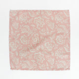 Pink and cream floral block print cloth napkin laid flat on a white background.