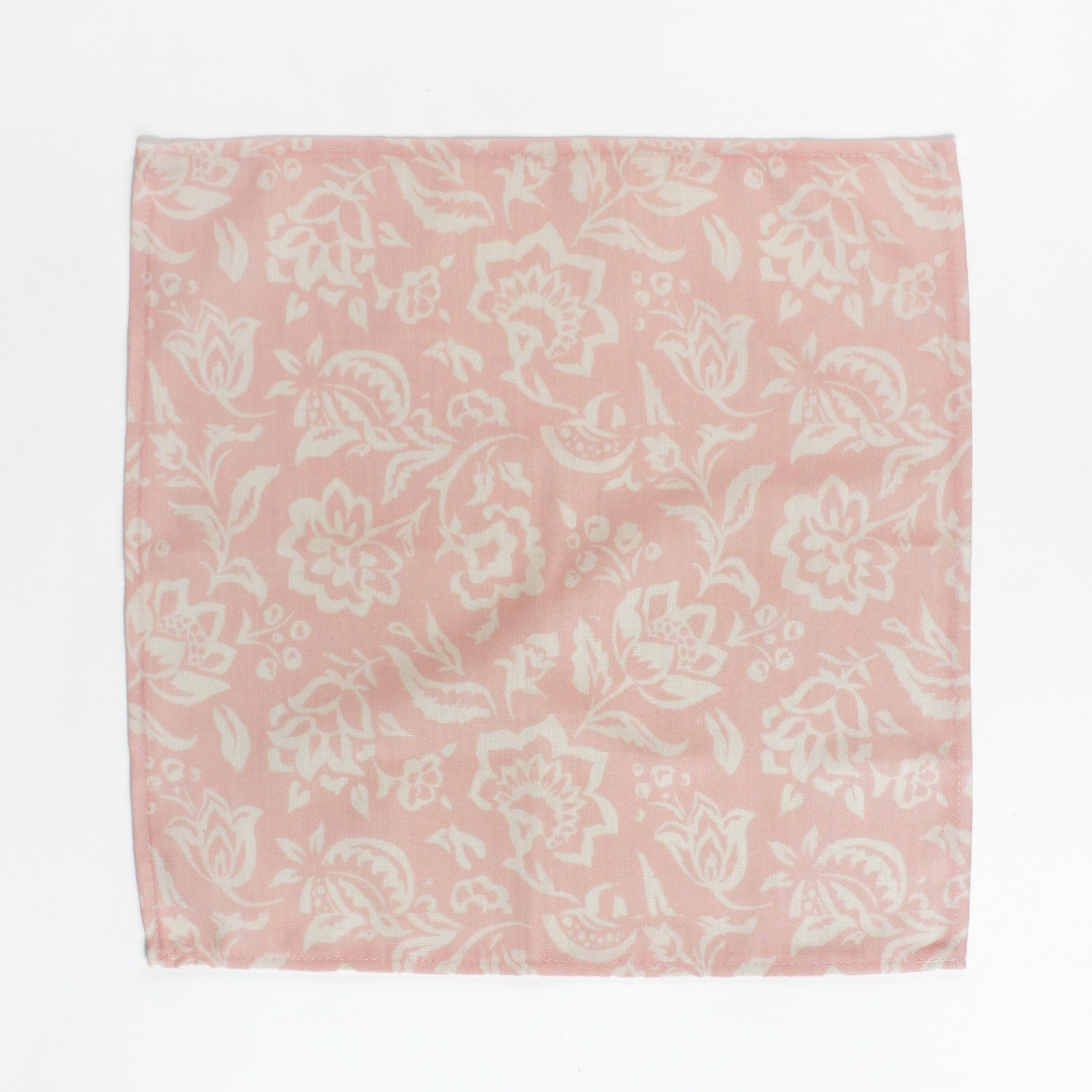 Pink and cream floral block print cloth napkin laid flat on a white background.