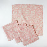 Set of four pink floral cotton cloth napkins displayed with one full napkin and three folded pieces on a white background.