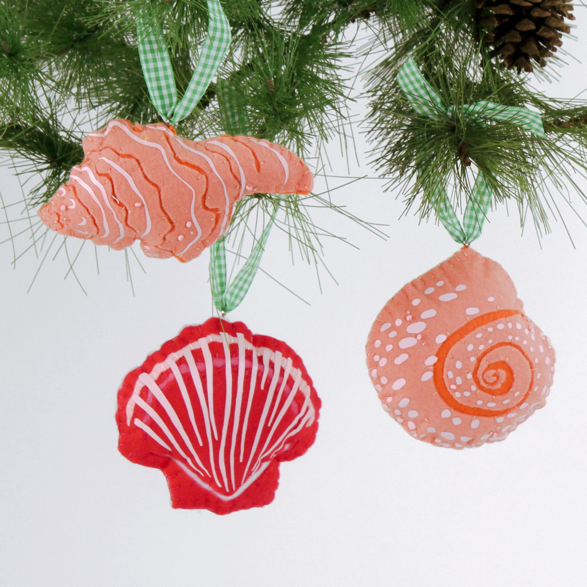 Handcrafted Pink Orange Shells Felt Christmas Ornaments featuring coral spiral, conch, and red scallop shell designs with green gingham ribbons.