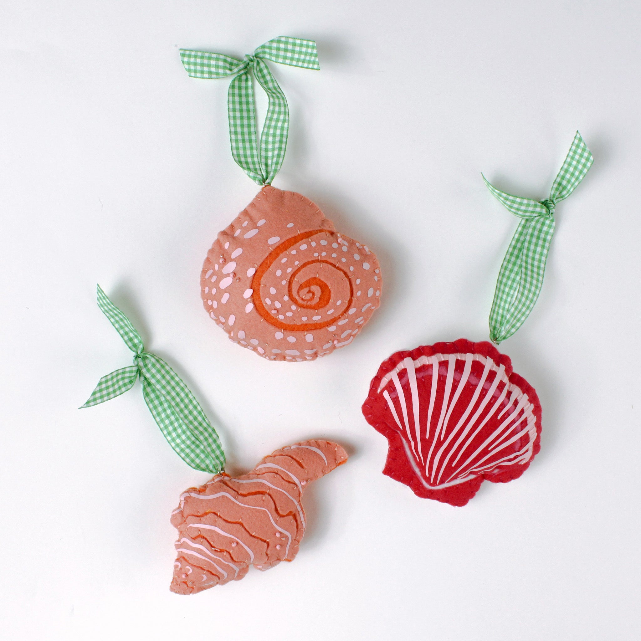 Handcrafted Pink Orange Shells Felt Christmas Ornaments featuring coral spiral, conch, and red scallop shell designs with green gingham ribbons.