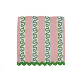 Pink tea towel with vertical green patterned stripes and scalloped green trim along the bottom edge.