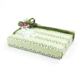 Green patterned Christmas gift box wrapped in light green paper with holly-inspired stripes and topped with a green ribbon and festive berry decoration.