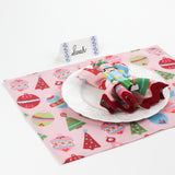 Side angle view of Harbor Trail Paper Place Card in blue displayed on a Christmas-themed table with pink placemat, nutcracker napkin, and white dinner plate.