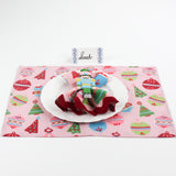 Christmas table setup featuring Harbor Trail Paper Place Card in blue with pink holiday placemat, nutcracker napkin ring, and white plate for festive dining decor.