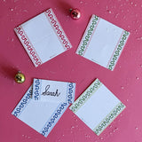 different colors of Harbor Trail Paper Place Cards scattered on a red surface with ball ornaments