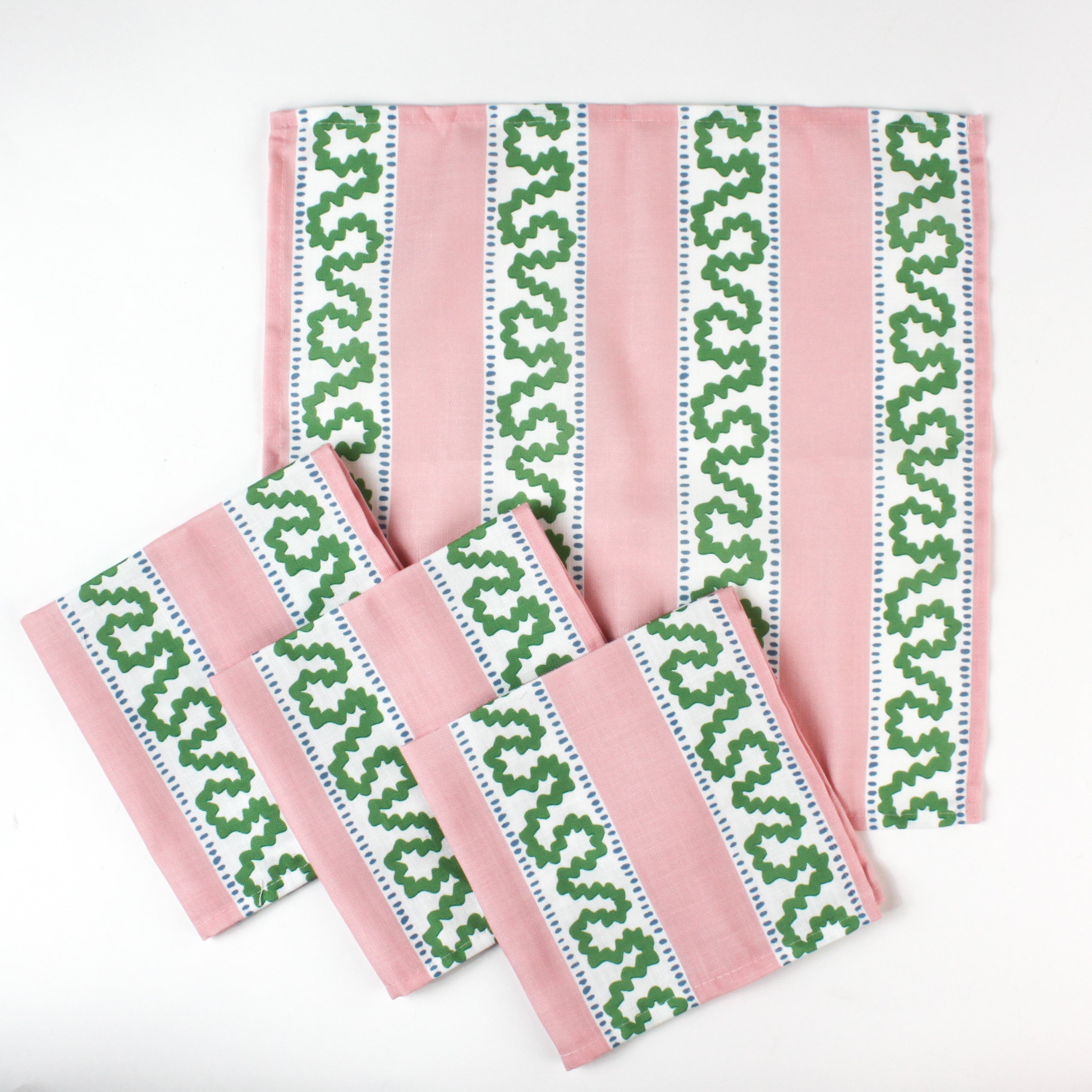 Set of handmade cloth napkins with pink stripes and green wavy trim pattern, displayed with matching dinner napkins for table decor.