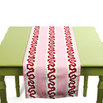 Pink and red patterned table runner displayed on a green table.