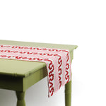 Side view of a pink and red patterned table runner draped over a green table.