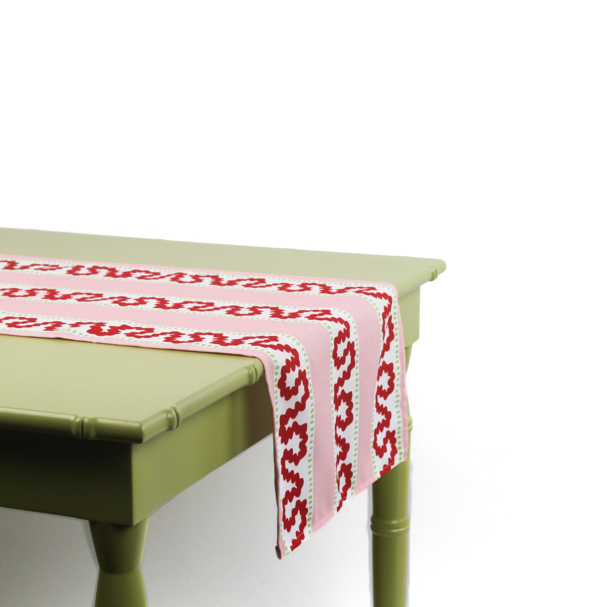 Side view of a pink and red patterned table runner draped over a green table.