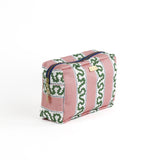 Front 3/4 view of Harbor Trail toiletry bag in Bahama pink with a green ribbon and blue dash motif.