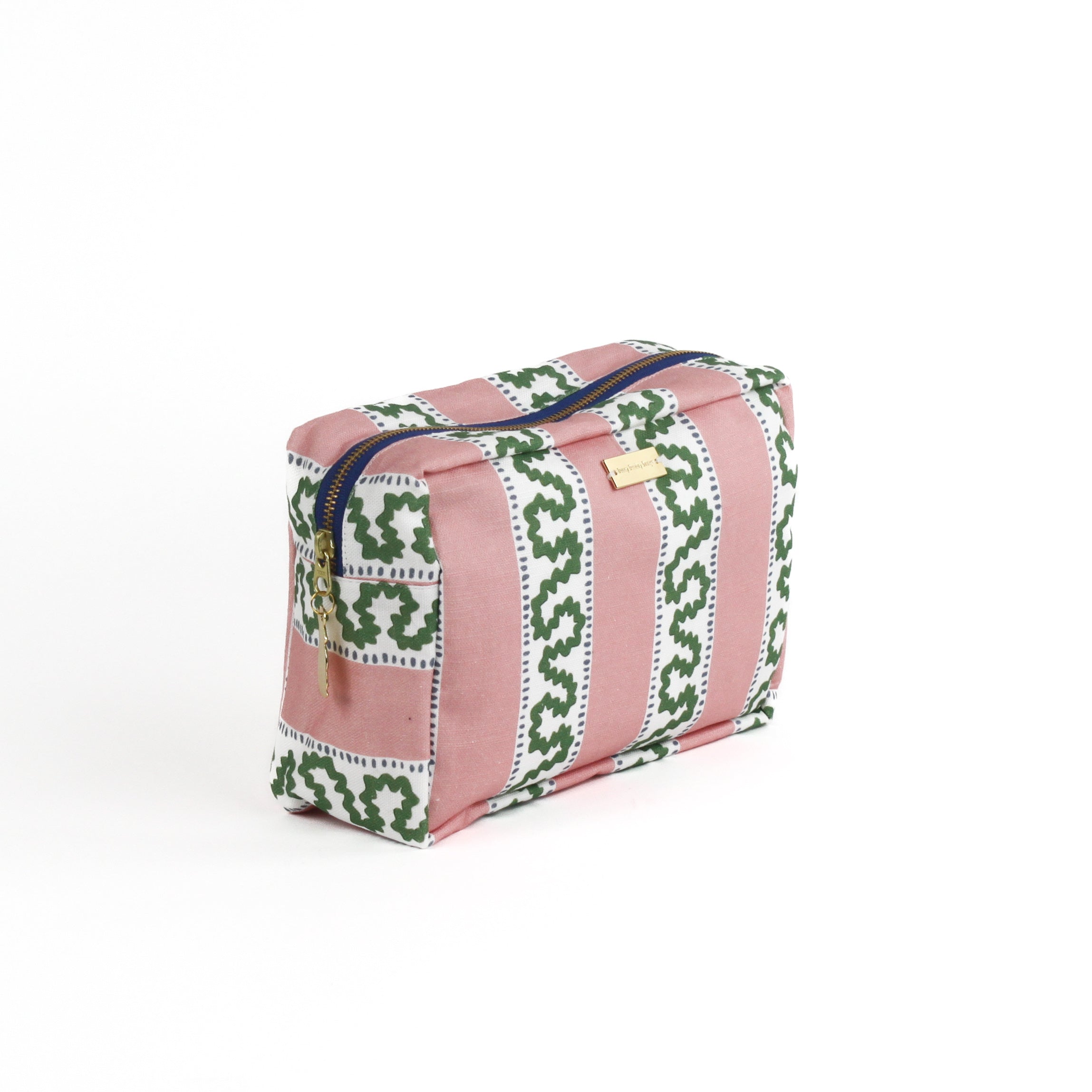 Front 3/4 view of Harbor Trail toiletry bag in Bahama pink with a green ribbon and blue dash motif.
