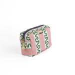 Front 3/4 view of Medium Harbor Trail toiletry bag in Bahama pink with a green ribbon and blue dash motif.