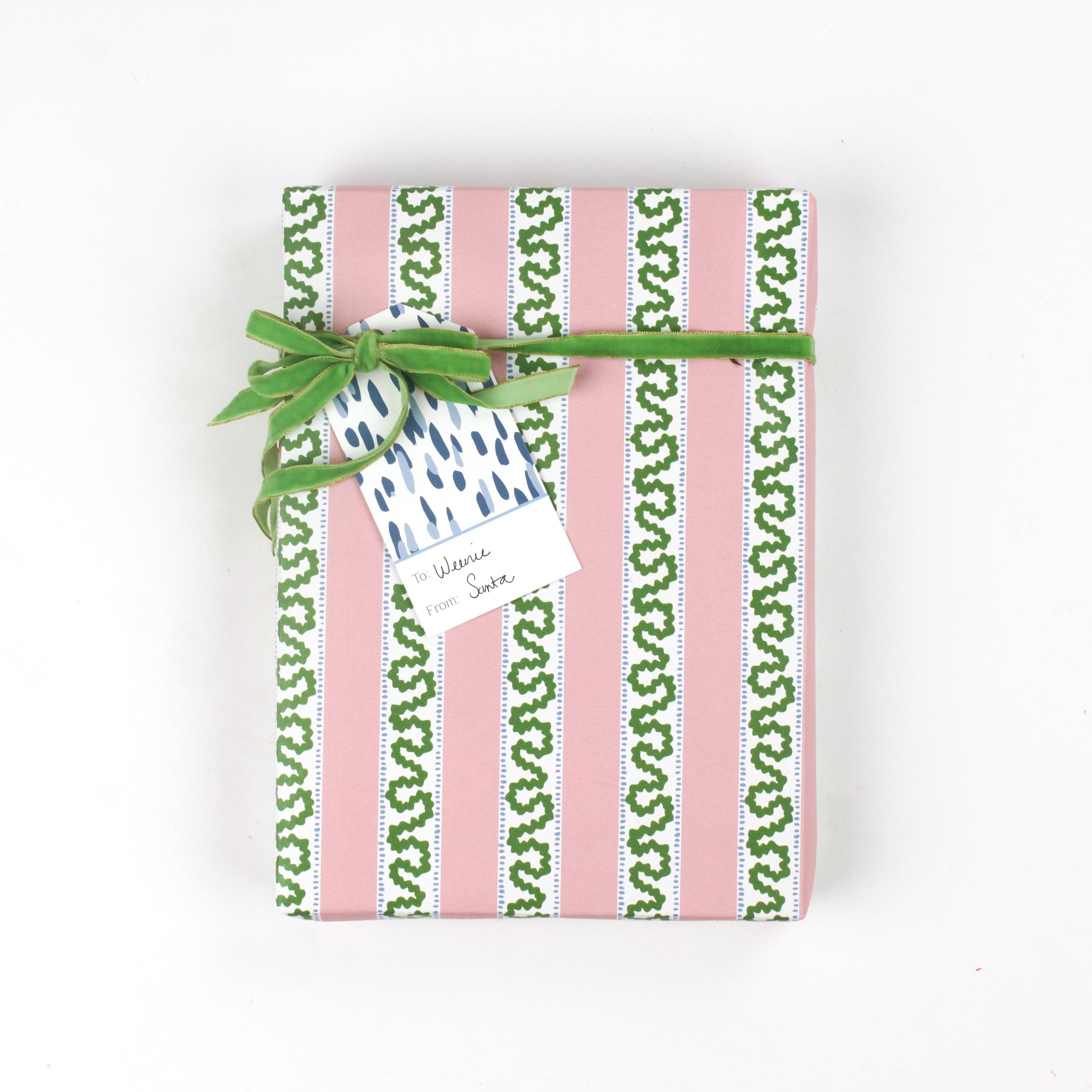 Front view of present wrapped in pink and green Christmas wrapping paper with green bow.