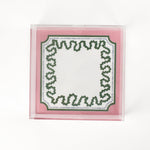 a square acrylic tray with a pink and green base featuring a green squiggle motif around the border.