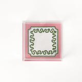 a square acrylic tray with a pink and green base featuring a green squiggle motif around the border.