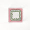 a square acrylic tray with a pink and green base featuring a green squiggle motif around the border.