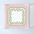a square acrylic tray with a pink and green base featuring a green squiggle motif around the border.
