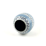 bottom view of a white, black and blue striped decorative Easter egg with on white background.