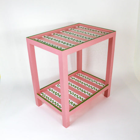 A pink side table with a green and white striped pattern named "Harbor Trail" by madcap cottage