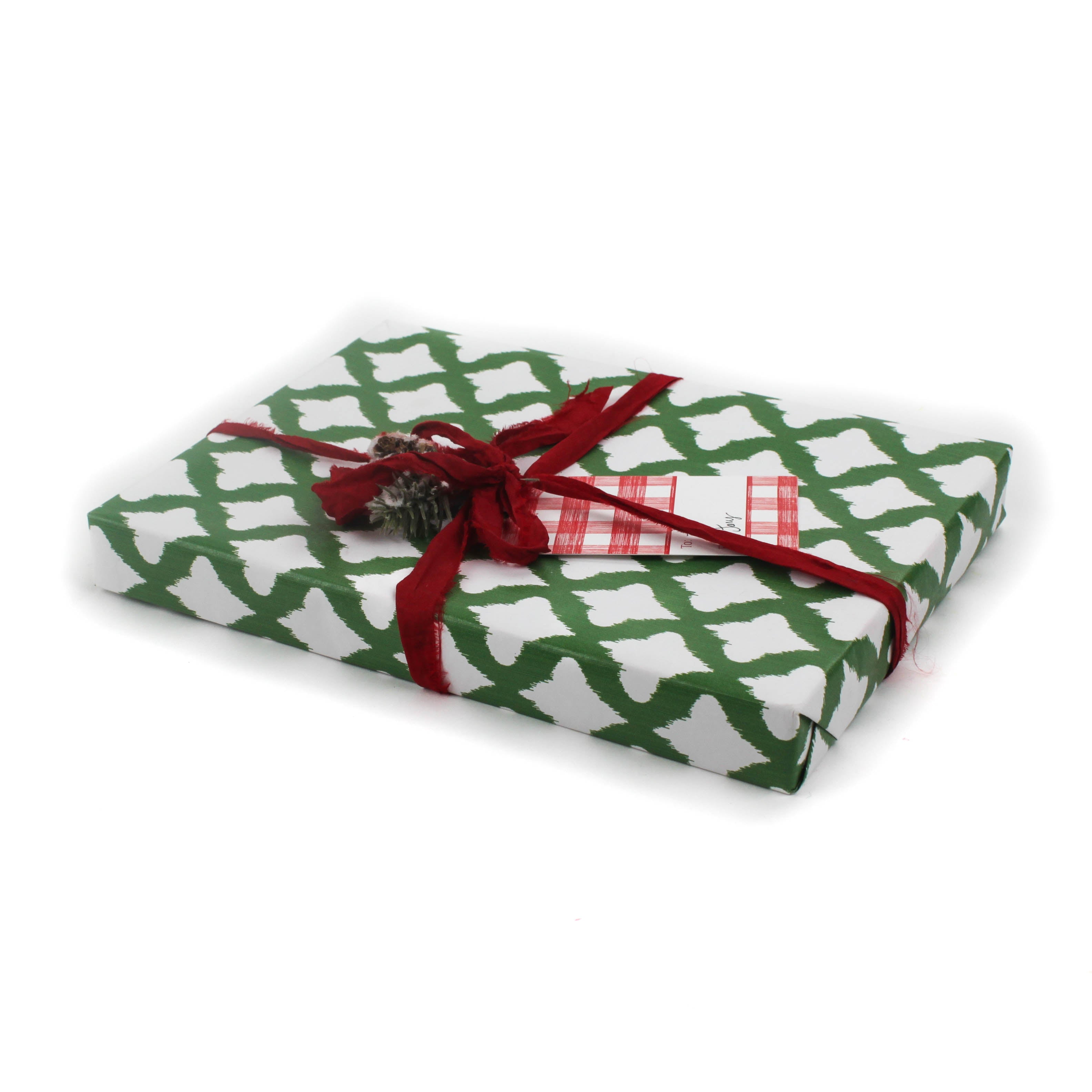 a gift wrapped in lattice print green and white wrapping paper with a red bow