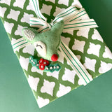 Gift wrapped in green and white patterned paper with striped ribbon and felt reindeer decoration.