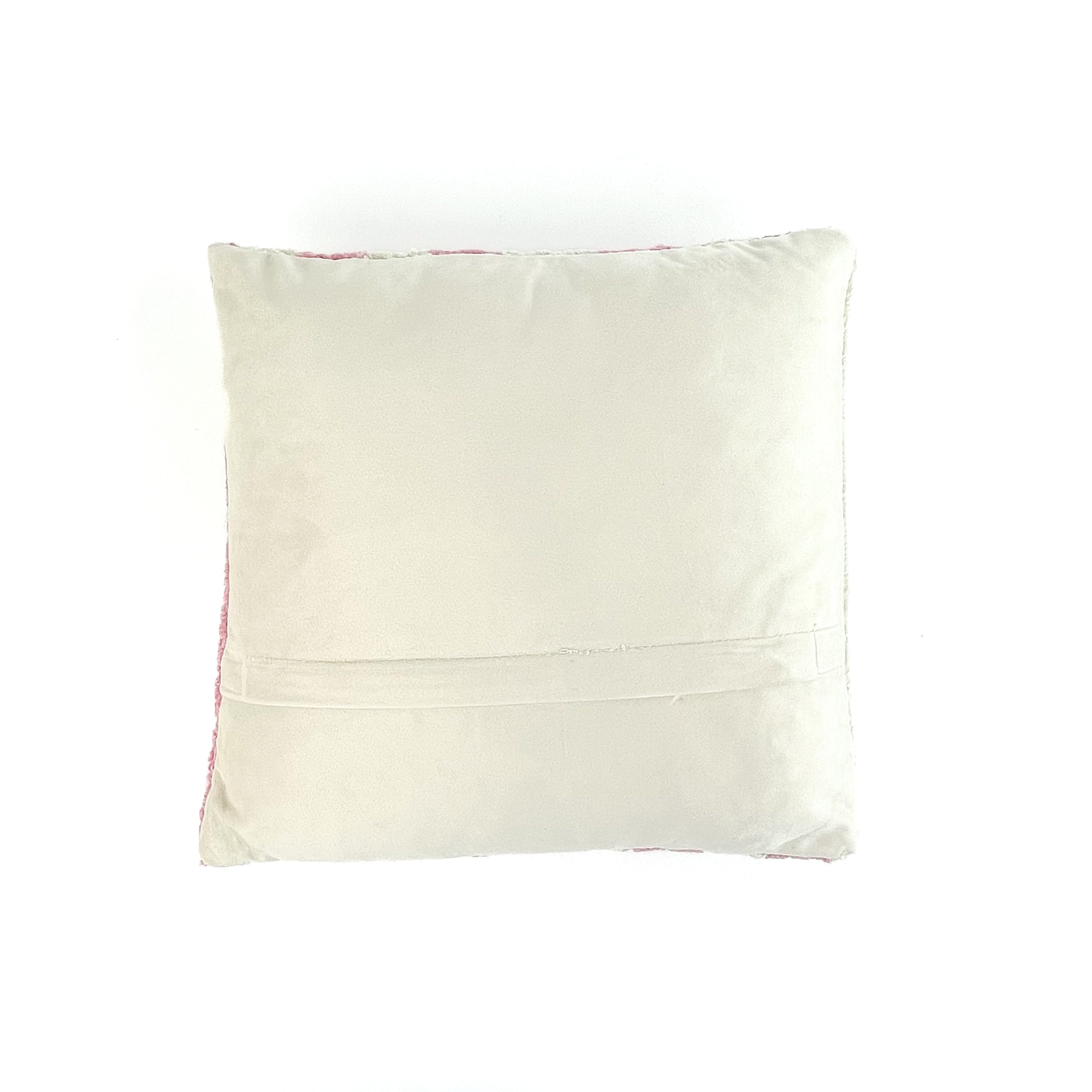 plain white velvet reverse side of a white and pink striped christmas pillow with holly design and red bow on a white background.