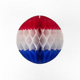 A red white and blue honeycomb paper ball decoration hanging against a white background.