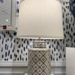 An illuminated small blue and white table lamp with a white lampshade