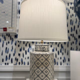 An illuminated small blue and white table lamp with a white lampshade