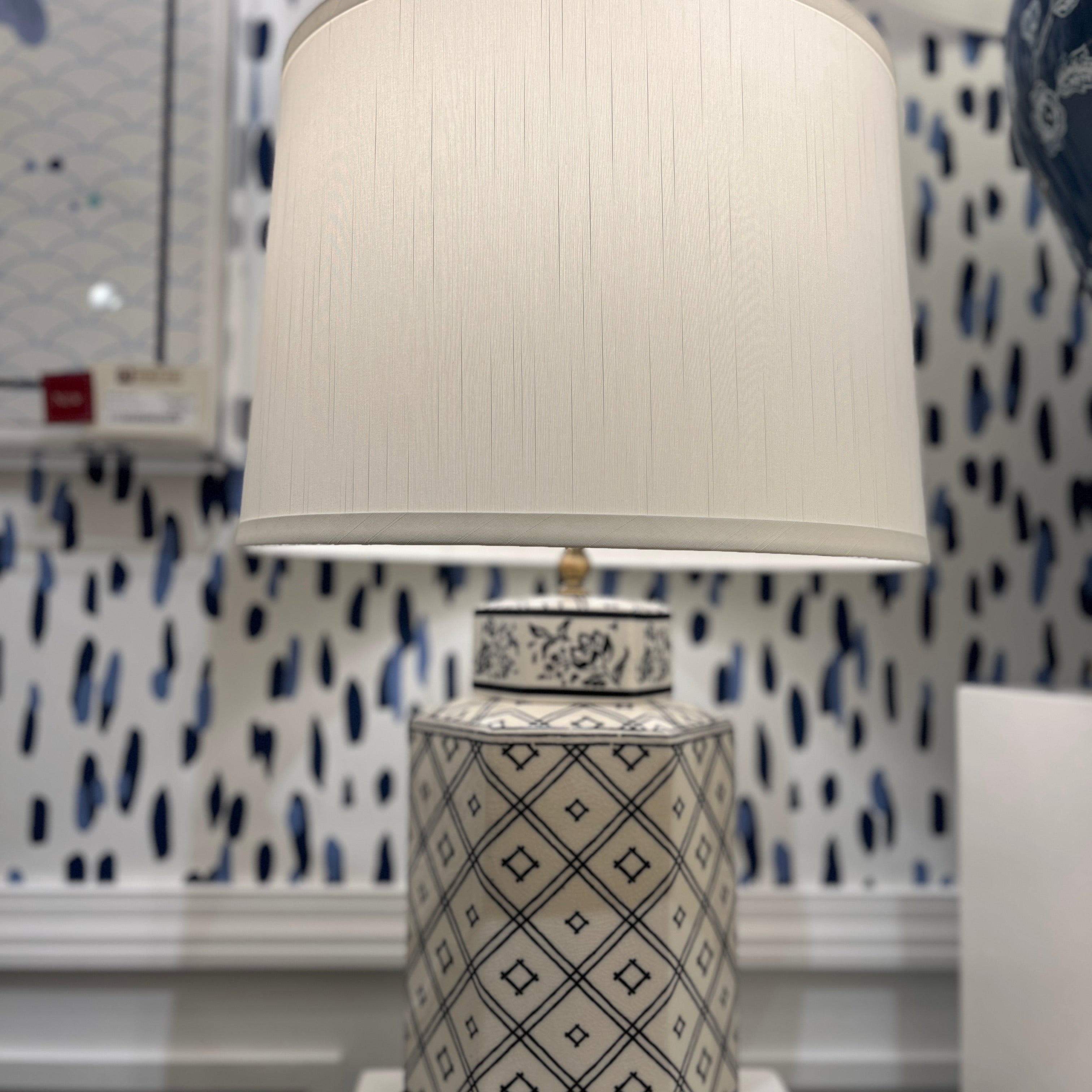 An illuminated small blue and white table lamp with a white lampshade