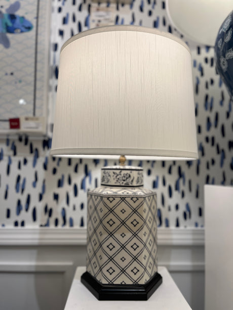An illuminated small blue and white table lamp with a white lampshade