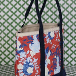 Front 3/4 view of Imperial Palace red canvas tote on a green and white background