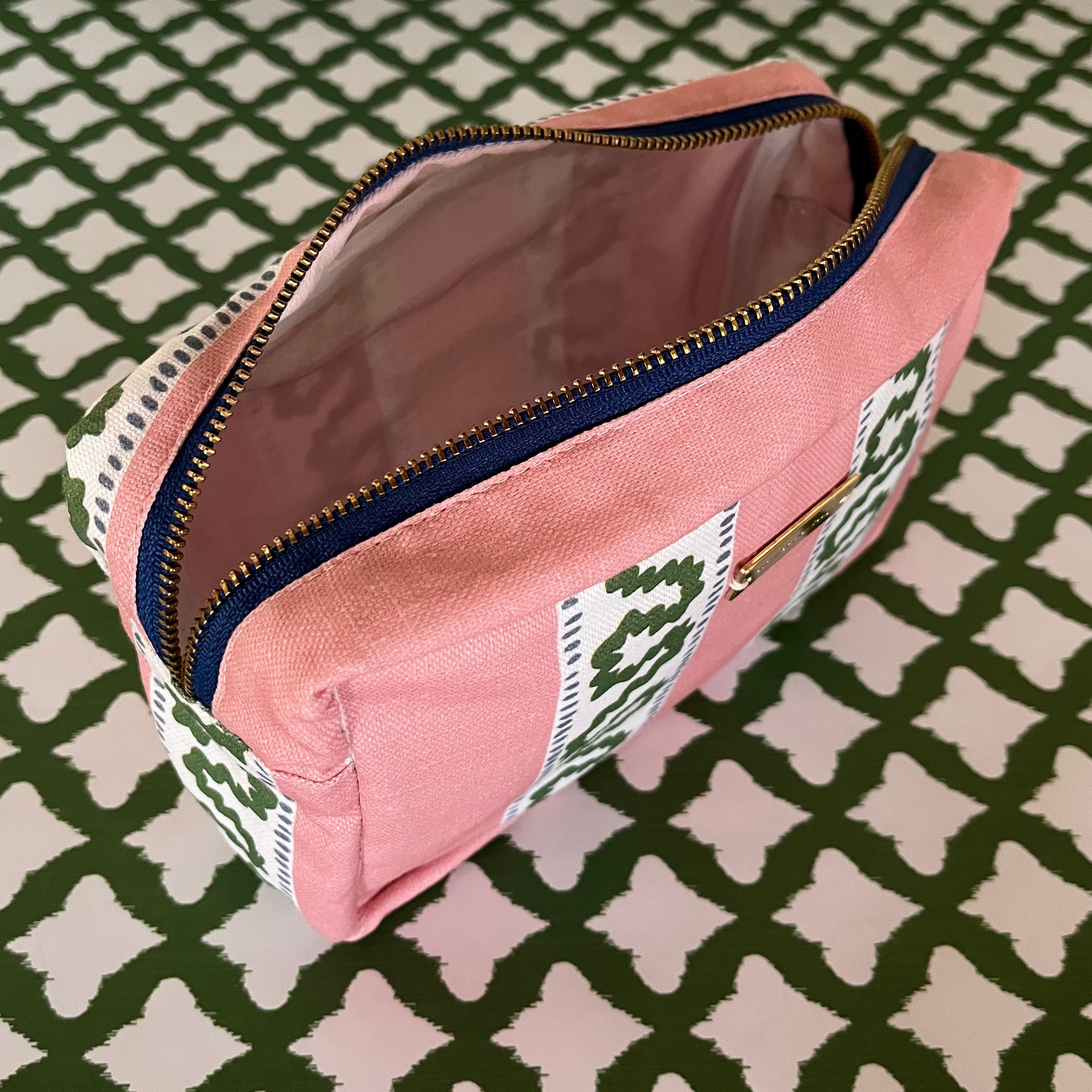 Interior view of Harbor Trail toiletry bag in Bahama pink with a green ribbon and blue dash motif.